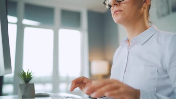 Woman with glasses typing on a computer keyboard. Concept of remote work. — Stock Video