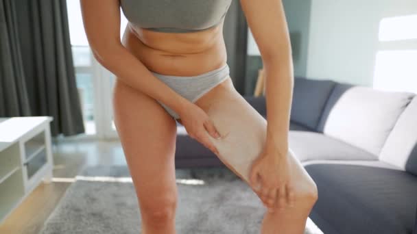 Женщина мажет ногу антицеллюлитным кремом и делает самомассаж. — стоковое видео