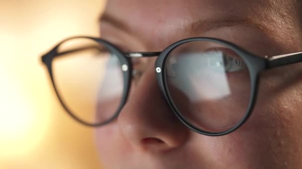 Mujer con gafas mirando en el monitor y navegando por Internet. La pantalla del monitor se refleja en las gafas. Trabaja de noche. Ministerio del Interior. Trabajo remoto — Vídeos de Stock