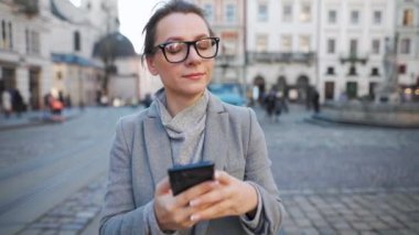 Eski bir sokakta yürüyen, etrafa bakıp fotoğraf çeken bir kadın. Yavaş çekim