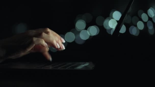 Ženský ruce píšou v noci na notebook. Rozmazaná světla na pozadí — Stock video