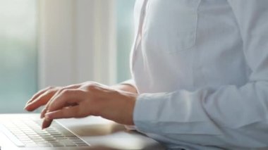 Yakın plan kadın rahat bir odada kanepede oturuyor ve bir dizüstü bilgisayar üzerinde çalışıyor. Uzak çalışma kavramı.