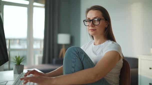 Vrijetijds geklede vrouw die thuis met een computer werkt in een gezellige omgeving. Werk op afstand buiten het kantoor. — Stockvideo