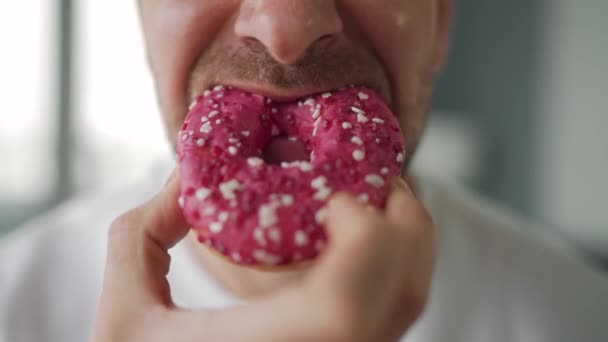 Un uomo che mangia ciambelle rosa dolci. Primo piano — Video Stock