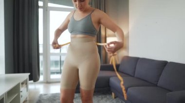 İnce iç çamaşırlı kadın ölçü ile bel ve kalça ölçülerini ölçer.