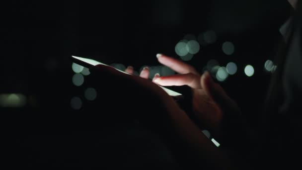 Mani femminili sta digitando su uno smartphone di notte. Luci sfocate sullo sfondo — Video Stock