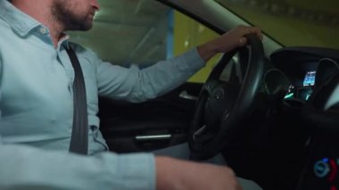 Adam yeraltı otoparkında araba sürüyor ve park edecek ya da gidecek bir yer arıyor. Yan görünüm
