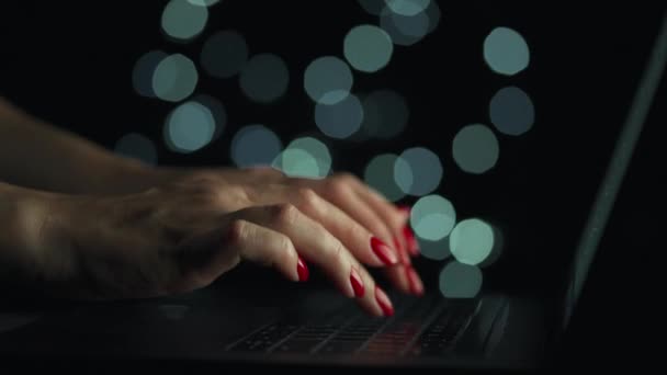 Жіночі руки друкують на ноутбуці вночі. Розмиті вогні на фоні — стокове відео