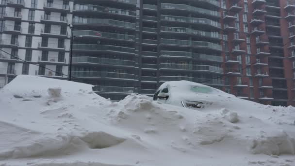 Auto 's bedekt met sneeuw na een sneeuwstorm. Woningbouw op de achtergrond. — Stockvideo