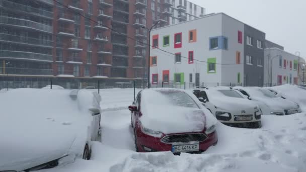 Lviv, Ukraine - 11 février 2021. Voitures couvertes de neige après un blizzard de neige. Bâtiment résidentiel en arrière-plan. — Video