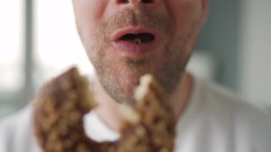 Çikolatalı tatlı çörek yiyen bir adam. Yakın plan.