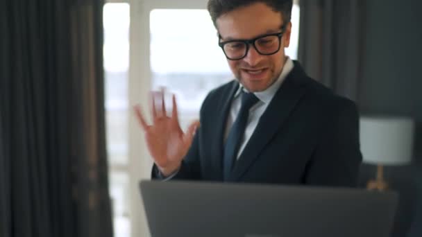 Homem caucasiano vestido com uma jaqueta e roupa interior usando laptop para fazer uma chamada de vídeo de casa em um apartamento moderno. Trabalho remoto durante uma pandemia — Vídeo de Stock