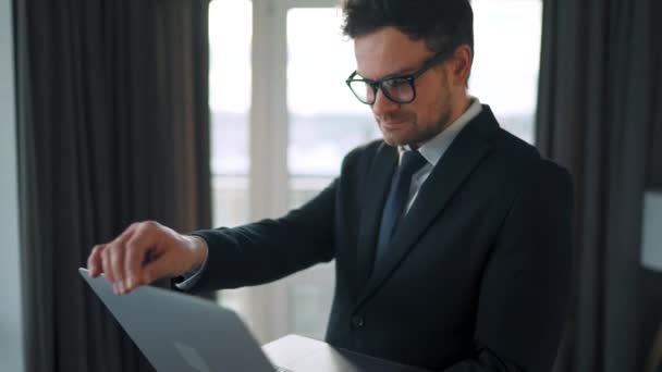 Blanke man gekleed in een jas en ondergoed met behulp van laptop om een videogesprek vanuit huis te plegen in een modern appartement. Afstandswerk tijdens een pandemie — Stockvideo