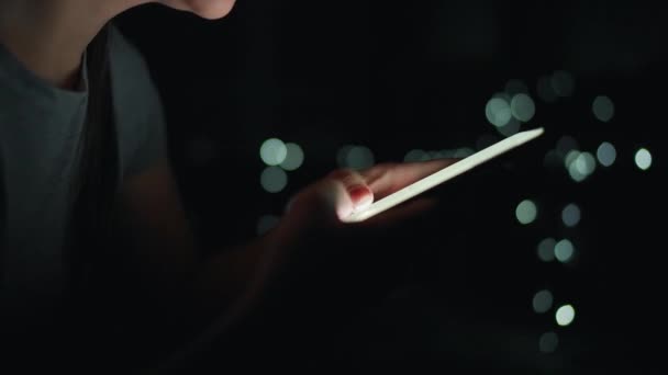 Vrouwelijke handen typen 's nachts op een smartphone. wazig licht op de achtergrond — Stockvideo