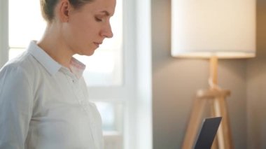 Yakın plan kadın rahat bir odada kanepede oturuyor ve bir dizüstü bilgisayar üzerinde çalışıyor. Uzak çalışma kavramı.