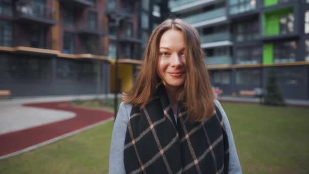 Portrait of a gorgeous dark haired woman smiling charmingly while standing against the background of modern buildings. Happy young woman enjoys life. Slow motion — Stock Video
