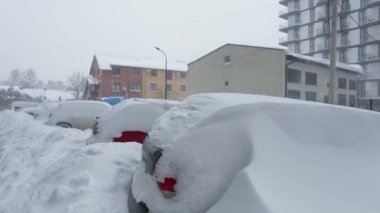Kar fırtınasından sonra arabalar karla kaplandı. Arka plandaki konut binası..