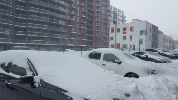 Auto 's bedekt met sneeuw na een sneeuwstorm. Woningbouw op de achtergrond. — Stockvideo