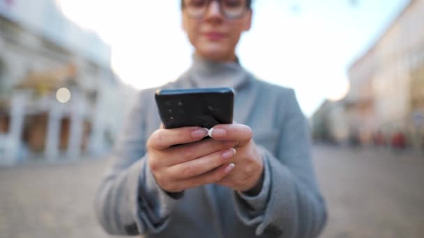 Eski bir caddede akıllı telefon kullanan bir kadın. Yakın plan. İletişim, sosyal ağlar, online alışveriş kavramı — Stok video