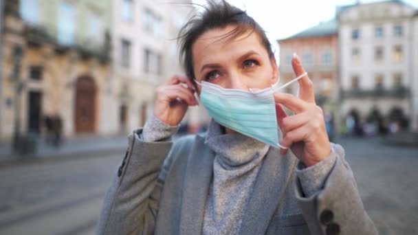 "Pandemic protection of the Covid-19 coronavirus". Femme dans un manteau se tient au milieu de la place, met un masque médical de protection. Mouvement lent — Video