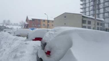 Kar fırtınasından sonra arabalar karla kaplandı. Arka plandaki konut binası..