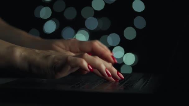 女性的手晚上在笔记本电脑上打字。背景上模糊不清的灯光 — 图库视频影像