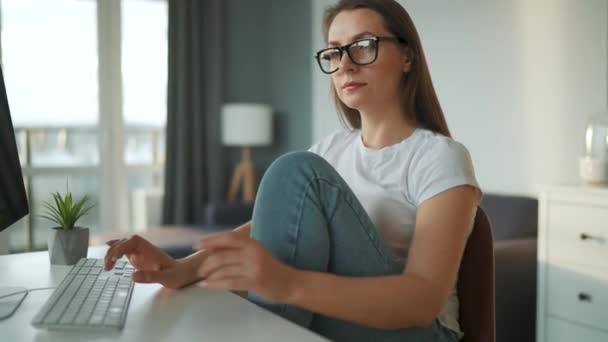 Mulher casualmente vestida trabalhando com um computador em casa em um ambiente acolhedor. Trabalho remoto fora do escritório. — Vídeo de Stock