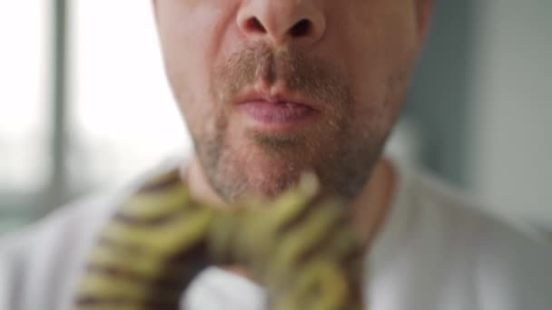 Un uomo che mangia ciambelle dolci al cioccolato. Primo piano — Video Stock