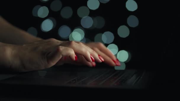 Kvinnliga händer skriver på en bärbar dator på natten. suddiga ljus på bakgrunden — Stockvideo