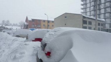 Kar fırtınasından sonra arabalar karla kaplandı. Arka plandaki konut binası..