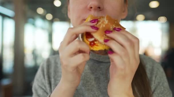 Femme mangeant un hamburger et des frites dans un café gros plan. Burger dans les mains des femmes. — Video