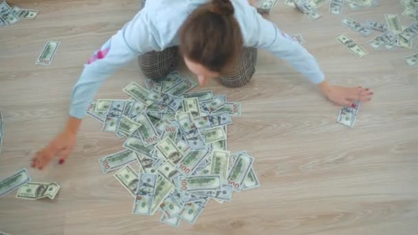A nő annyi amerikai dollárt halmoz fel a padlón, amennyit csak lehetséges. — Stock videók