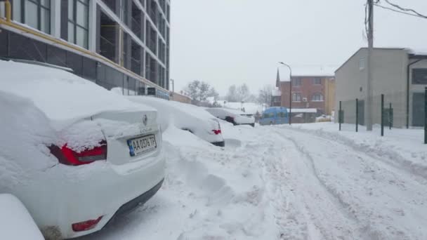 Lvov, Ukrajina - 11. února2021. Auta pokrytá sněhem po sněhové bouři. Rezidenční budova v pozadí. — Stock video