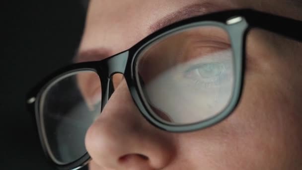 戴眼镜的女人看着监视器，用图表和分析仪器工作。显示器屏幕反映在眼镜上.晚上工作。2.极端密切的情况 — 图库视频影像