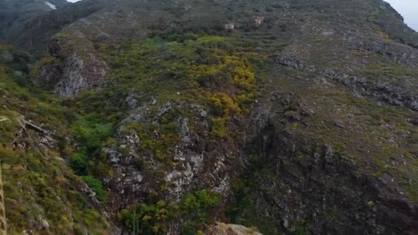 Vista aérea de una superficie montañosa rocosa cubierta de escasa vegetación. Se ha instalado una línea eléctrica a lo largo de la cresta. Tenerife, Islas Canarias, España — Vídeos de Stock