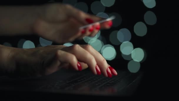 Mains féminines tapant le numéro de carte de crédit sur le clavier de l'ordinateur pour faire des achats en ligne la nuit. Service de paiement en ligne. — Video