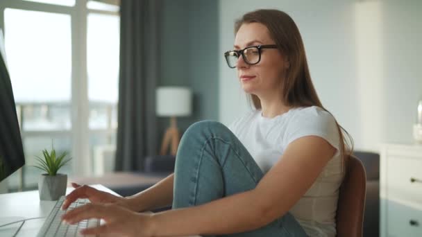 Vrijetijds geklede vrouw die thuis met een computer werkt in een gezellige omgeving. Werk op afstand buiten het kantoor. — Stockvideo