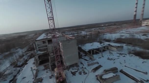 FPV insansız hava aracı, terk edilmiş sanayi binaları ve bir kazıcının etrafında hızla ve manevra kabiliyetiyle uçar.. — Stok video