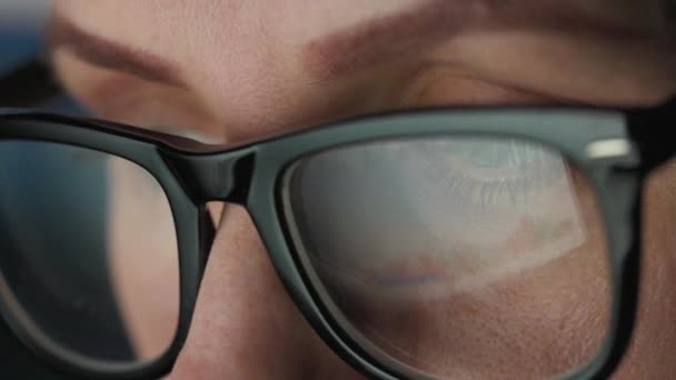 Woman in glasses looking on the monitor and and working with charts and analytics. The monitor screen is reflected in the glasses. Work at night. Extreme close-up — Stock Video