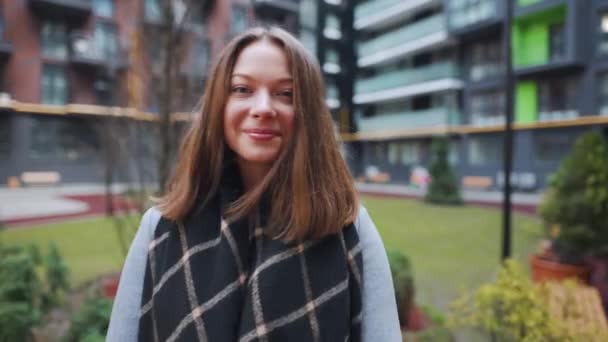 Portret van een prachtige donkerharige vrouw die charmant lacht terwijl ze tegen de achtergrond van moderne gebouwen staat. gelukkig jong vrouw geniet van het leven. — Stockvideo