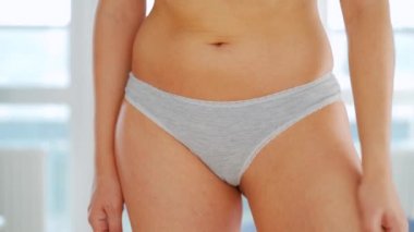 Kadın bacağına anti-selülit kremi sürüyor ve kendine masaj yapıyor.