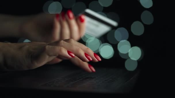 Manos femeninas escribiendo el número de tarjeta de crédito en el teclado de la computadora para hacer la compra en línea por la noche. Servicio de pago en línea. — Vídeo de stock