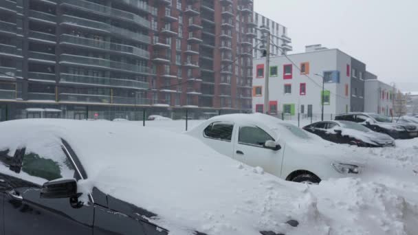 Samochody pokryte śniegiem po śnieżycy. Budynek mieszkalny w tle. — Wideo stockowe