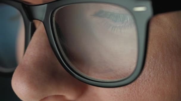 Woman in glasses looking on the monitor and and working with charts and analytics. The monitor screen is reflected in the glasses. Work at night. Extreme close-up — Stock Video