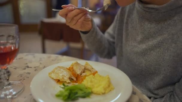 女性はカフェで昼食をとっている。魚やマッシュポテトを食べる — ストック動画