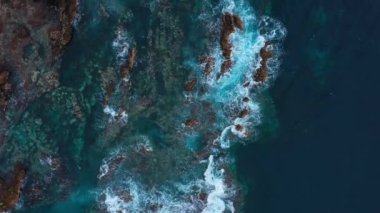 Issız bir sahil manzarası. Tenerife adasının kayalık kıyısı. Deniz dalgalarının kıyıya ulaşan hava aracı görüntüleri.