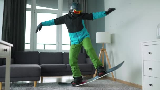 有趣的视频。打扮成滑雪者的人在舒适的房间里把滑雪板放在地毯上。等待着一个多雪的冬天. — 图库视频影像