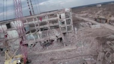 FPV insansız hava aracı, terk edilmiş sanayi binaları ve bir kazıcının etrafında hızla ve manevra kabiliyetiyle uçar..