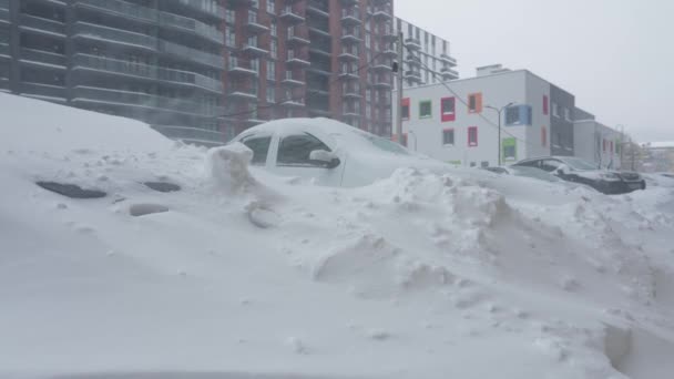 Auto 's bedekt met sneeuw na een sneeuwstorm. Woningbouw op de achtergrond. — Stockvideo