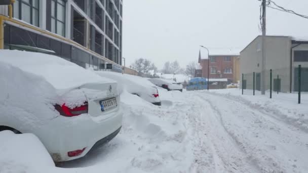 Lvov, Ukrajina - 11. února2021. Auta pokrytá sněhem po sněhové bouři. Rezidenční budova v pozadí. — Stock video